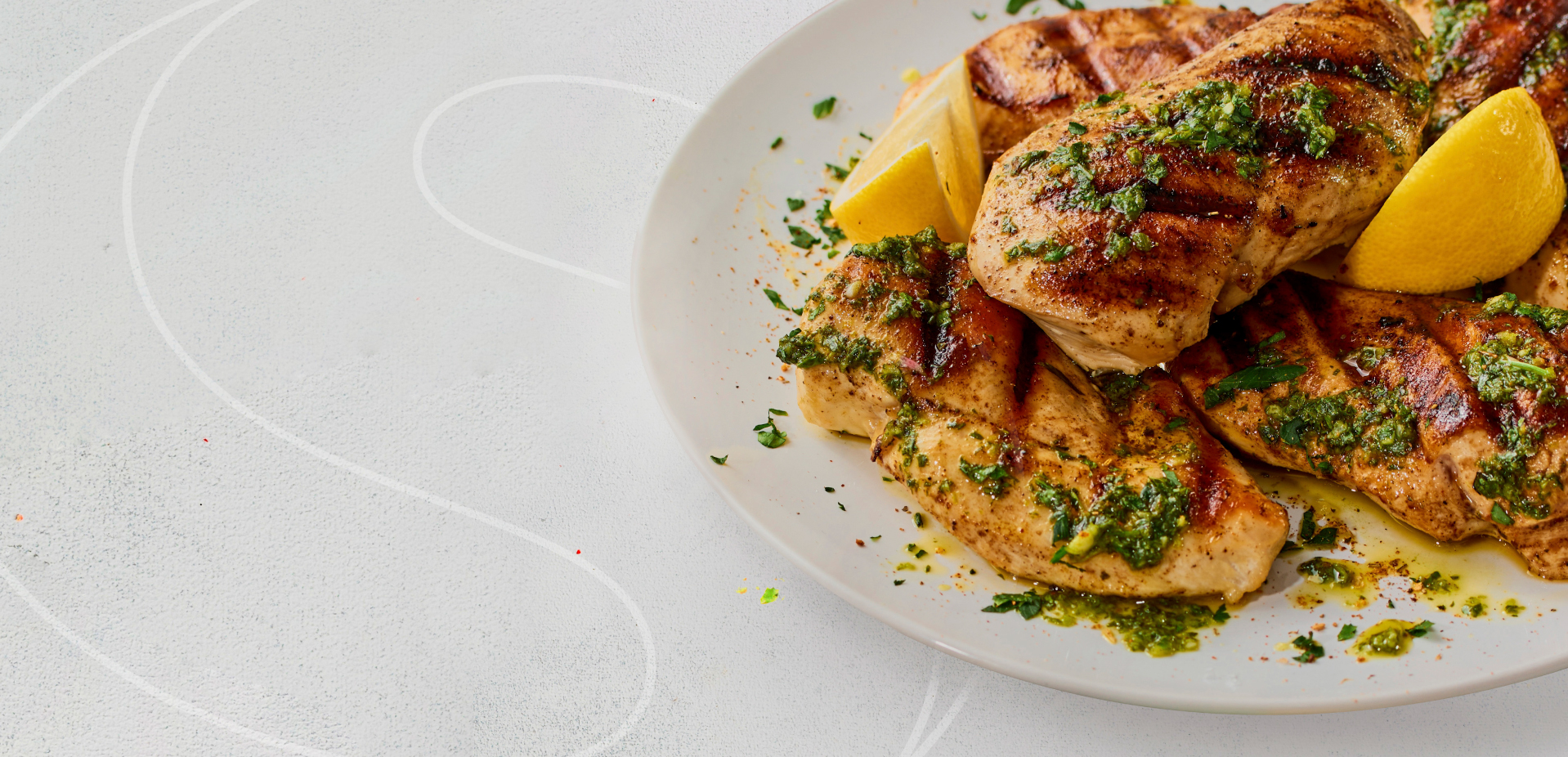 A plate Cater Chicken Breast Fillets grilled and topped with a pesto and lemons