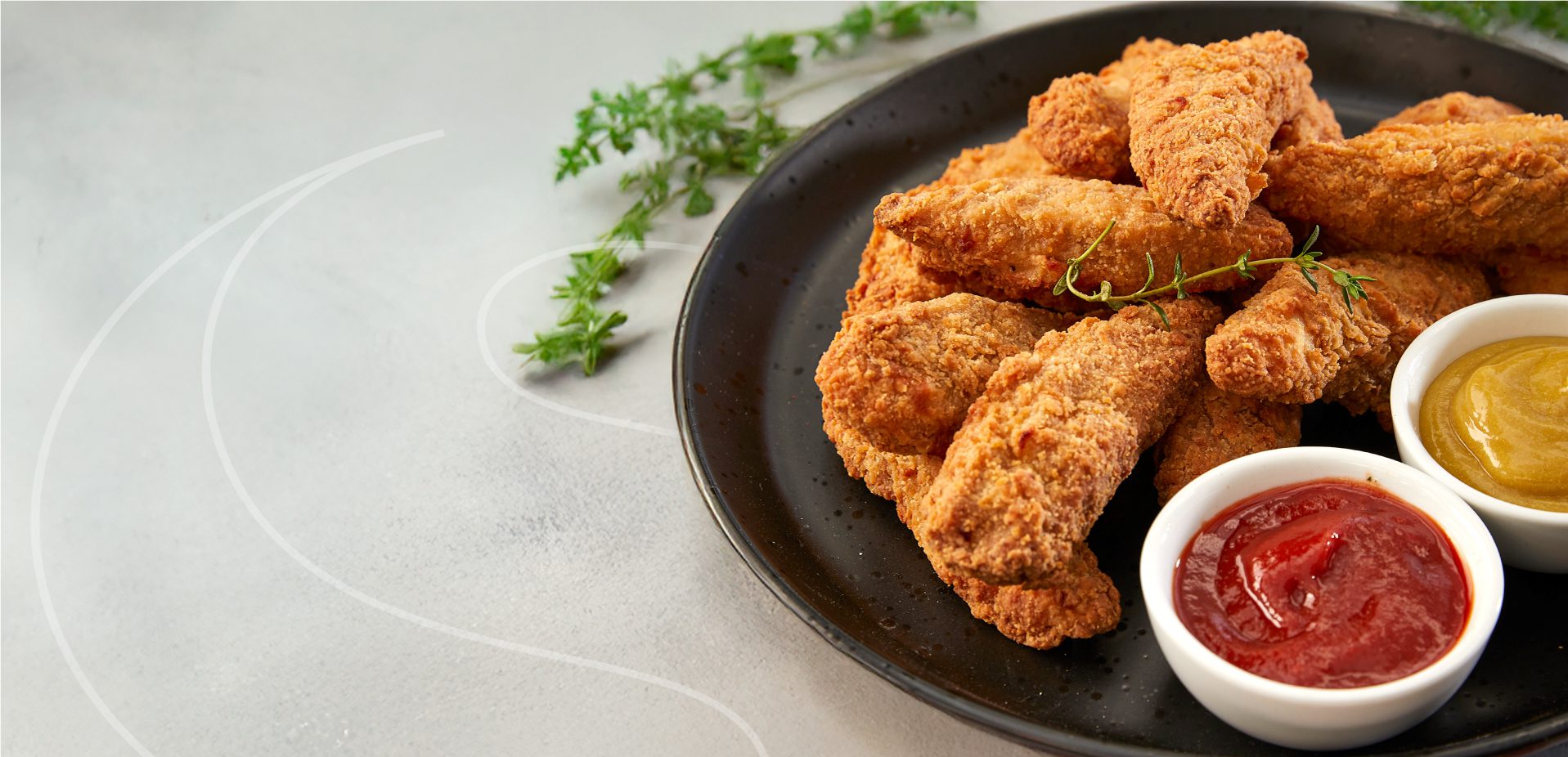A Plate of Sovereign Chicken Strips with two small dips of tomato sauce and mustard